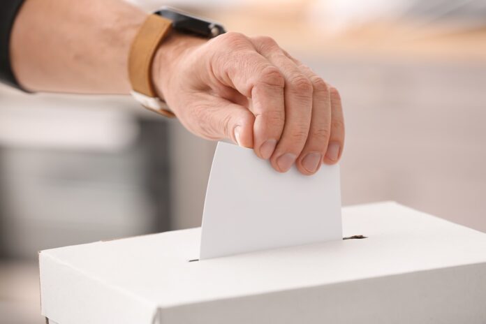 Voting young man near ballot box
